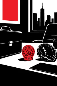 A small ornate golden skull on a corporate desk between a briefcase and a baseball glove.