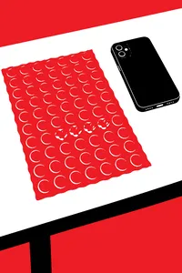 A sheet of bubble wrap on a desk with a few bubbles popped in a neat row, a phone face down beside it.