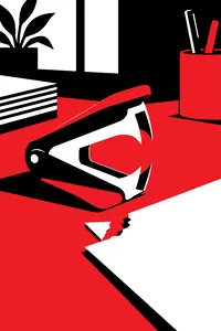 A staple remover with its jaws open on a desk beside a torn page corner.