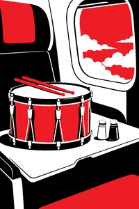 A brass marching drum on an airplane tray table next to tiny salt and pepper shakers, clouds out the window.