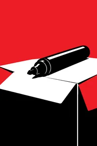 A black permanent marker with its cap missing, lying across a cardboard flap, a dried-out tip pointing at the viewer.