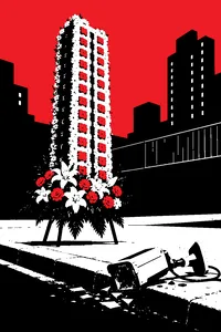 A funeral flower arrangement shaped like a tall housing-project tower, standing beside a smashed surveillance camera on a curb.