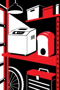 A boxy white bread maker on a garage shelf next to a tall loaf with a hole in its base.